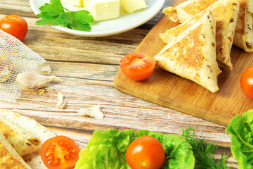 Fried homemade fast food, on a wooden board with herbs and a fork, tortilla with an hour and cheese