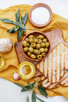 Overhead view of slices of ciabatta toast with green olives, olive oil and fresh garlic