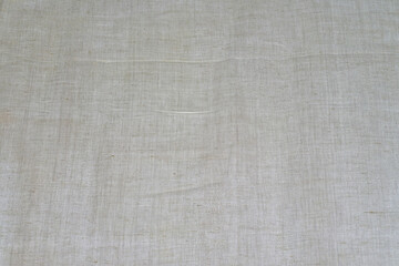Light beige background made of old linen fabric with spots.