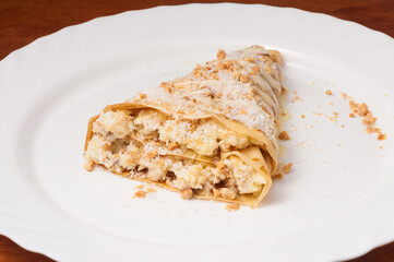 crepe with banana and coconut shavings on a white plate