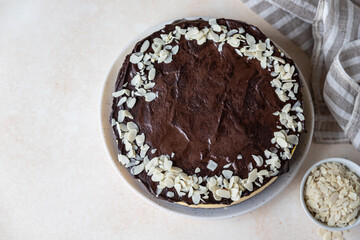 Delicious creamy cheesecake decorated with chocolate glaze and almond, light concrete background. No bake mousse dessert.