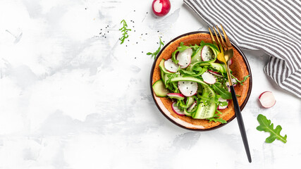Vegetable salad of fresh cucumbers, radish and arugula. Diet detox food concept. banner, menu recipe place for text, top view