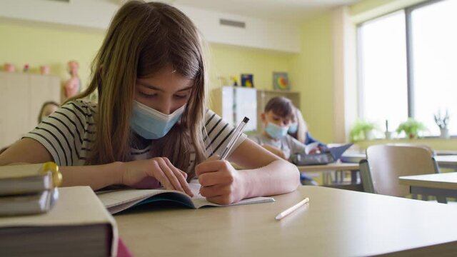 Video  of schoolgirl in protective mask writing in notebook. Shot with RED helium camera in 8K