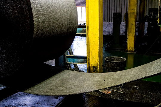 Close up of a roll of rubber on a machine in a conveyor belt factory
