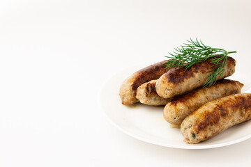 Fried sausage on a white plate on a white plate with herbs