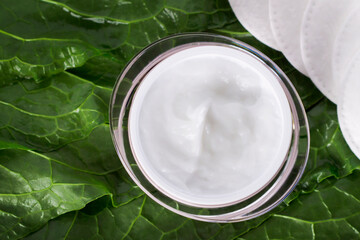 Hair balm. A jar of face cream on fresh leaves.