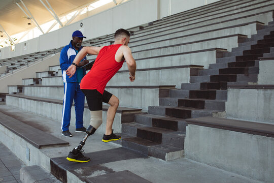 Caucasian male athlete with prosthetic leg climbing on the stairs of the stadium