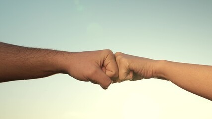 Fototapeta na wymiar Male and female fists against the sky, trust, harmony, friendship. A fist to a fist is a sign, expresses consent, a gesture of respect. Teamwork concept. Lifestyle business team hands fists close up.