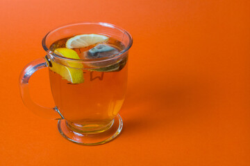 A cup of tea with lemon in a close-up on an orange background