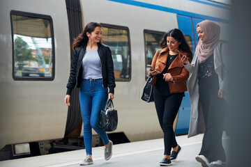 Smiling female friends at train station platform