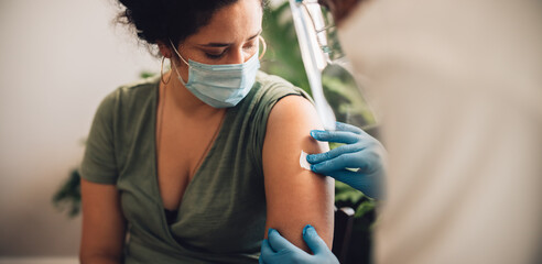 Woman receiving covid vaccine at home - obrazy, fototapety, plakaty