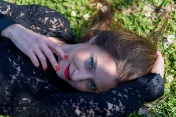 Outdoors closeup of beautiful girl with brown hair lying on the grass.
