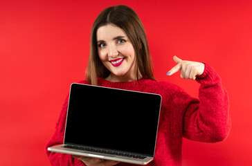 Close-up portrait photo of beautiful happy smiling girl with long hair wearing red hoodie holding computer laptop
