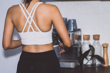 Asian women in gym clothes making coffee in Kitchen, She is standing with her back to the camera