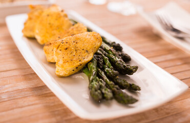 cooked dish. Chicken nuggets with green asparagus on plate