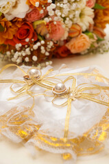 pillow with gold wedding rings decorated with flowers. Vertical frame