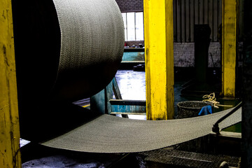 Close up of a roll of rubber on a machine in a conveyor belt factory