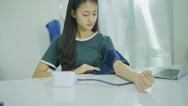 Slow-motion,Asian woman Self monitoring , analysing, check blood pressure. Healthcare equipment, devices at home. Thai woman measure blood pressure in BP watch device At home.