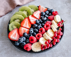Fresh fruit platter with strawberry, raspberry, banana, blueberry, kiwi fruit and redcurrant