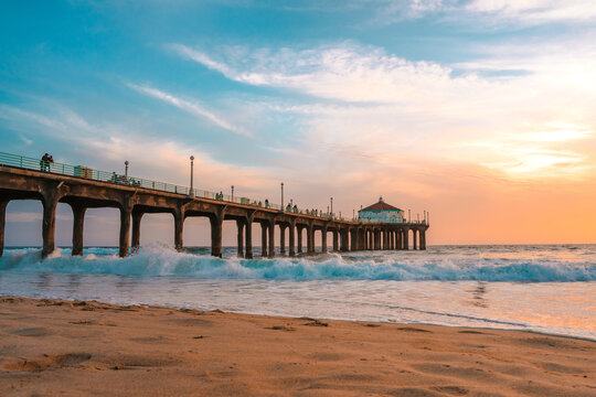 Manhattan beach pier at sunset, orange-pink sky with bright colors, beautiful landscape with ocean and sand