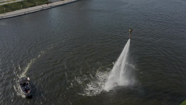 A man with a girl flies over the river on a flyboard and dives into the water. Flyboarding is a new extreme water sport. a man performs tricks in flight. Spectacular sports coups and turns. 