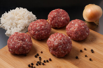 raw beef meatballs with rice on a wooden Board