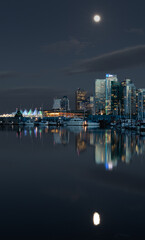 Fototapeta na wymiar Picture of downtown vancouver canada on a clear night with a full moon, taken from Stanley park