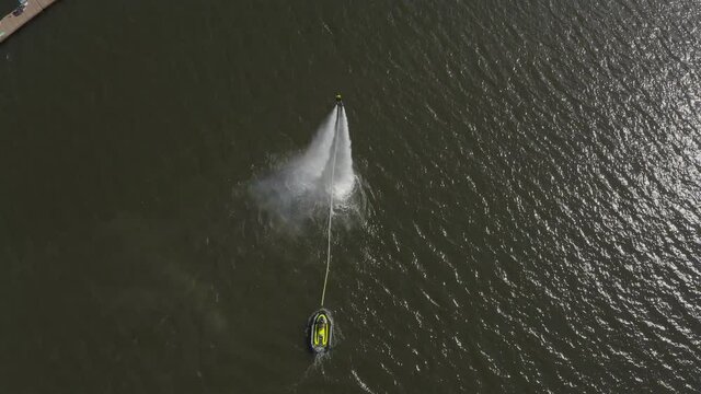 A man flies over the river on a flyboard and dives into the water. Flyboarding is a new extreme water sport. a man performs tricks in flight. Spectacular sports coups and turns. aerial view