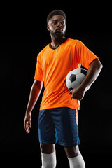 Portrait of young African soccer player posing isolated on black background. Concept of sport.