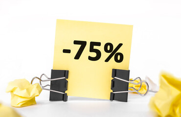 minus 75 percent on a yellow piece of paper for notes. Stationery Paper clips, crumpled paper. financial business concept. sale, discounts.