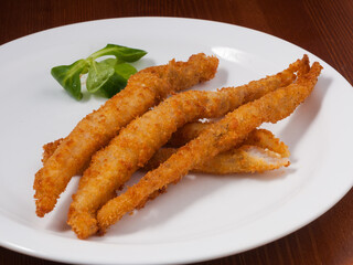 tasty fish sticks in batter handmade on a white plate