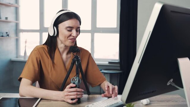 Woman blogger or vlogger streaming online on social media to her subscribers. Woman using microphone and computer for video calll