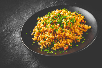 Bulgur with vegetables on black plate on Dark grey black slate background