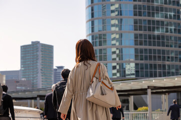 朝の通勤をする歩く女性の後ろ姿