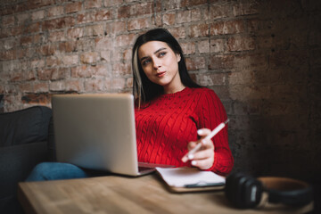 Young thoughtful female working on laptop