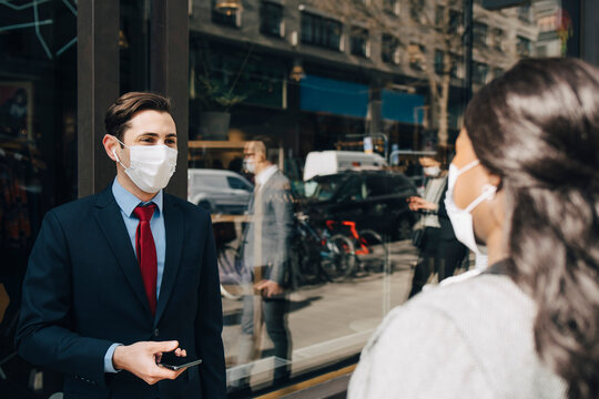 Businessman in face mask talking with female colleague during pandemic