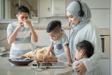 Multitasking mother, work with her laptop and taking care of the family