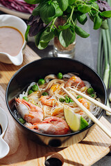 romantic dinner for two. Asian cuisine, rice noodles with shrimp and seafood, green peas and onions. soy sauce and various fresh vegetables. romantic dinner in black plates with Japanese chopsticks