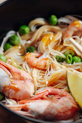 romantic dinner for two. Asian cuisine, rice noodles with shrimp and seafood, green peas and onions. soy sauce and various fresh vegetables. romantic dinner in black plates with Japanese chopsticks