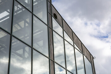The sky is reflected in the glass surface of the building wall
