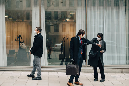 Male Entrepreneur Doing Elbow Bump With Female Colleague Outside Store During Pandemic