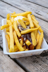 Portion of french fried potato chips with curry and mayonnaise sauce and onion