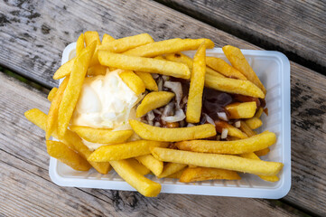 Portion of french fried potato chips with curry and mayonnaise sauce and onion