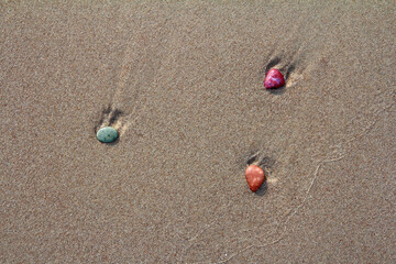 Calm, relaxing landscape of beautiful colorful pebbles stones in sand in beach, color close up photo for decoration.
