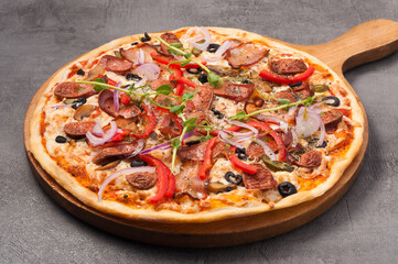 pizza with bacon and hunting sausages on a gray background