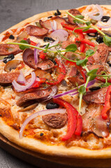 pizza with bacon and hunting sausages on a gray background. close up