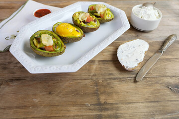 baked avocado stuffed with egg, vegetables, lie on a white dish, bread smeared with curd mass, linen napkin with embroidery, concept of post-holiday detox, diet, healthy food