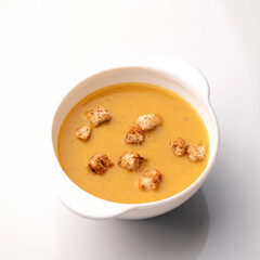 Bowl of soup with curry and croutons on white background. Spicy oriental dish. Pan-Asian cuisine. Top view.
