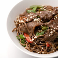 Wok Brown Spaghetti with meat, onion. Food plate isolated on white background, Top view. Appetizer noodle dish from restaraunt menu. Spicy oriental dish, Pan-Asian cuisine. Soft focus.