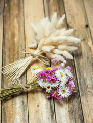 Dekoration mit Trockenblumen auf hölzernen Untergrund, getrocknete Gräser und Blumen
